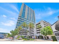 Contemporary high-rise building with modern architecture, blue glass windows, and lush palm trees at 150 E Robinson St # 2408, Orlando, FL 32801