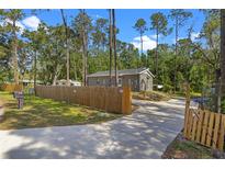 Charming home featuring a wooden fence, mailbox, and driveway leading to the house surrounded by trees at 1611 Creekwood Run, Lakeland, FL 33809