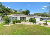 Well-maintained single-story home featuring manicured landscaping, lush green lawn and charming curb appeal on a sunny day at 428 Tarrson Blvd, Lady Lake, FL 32159