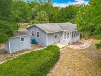 Charming one-story home featuring light blue siding, a screened porch, and a lush, green hedge at 499 W Beresford Rd, Deland, FL 32720