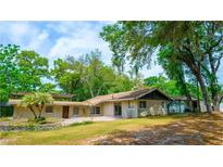 Sprawling single-story home with mature trees, a covered patio, and a well-manicured lawn, offering a serene outdoor experience at 530 Webster St, Lake Mary, FL 32746