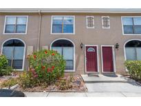 Charming townhome exterior with red doors, blooming hibiscus, and well-maintained landscaping at 611 Casa Park A Ct, Winter Springs, FL 32708