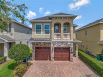 Charming two-story home showcasing a stone facade, a brick driveway, and a second story balcony at 7564 Marker Ave, Kissimmee, FL 34747