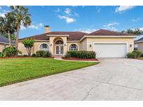 Charming single-story home with manicured lawn, arched entryway, two-car garage, and mature palm trees at 1024 Featherstone Cir, Ocoee, FL 34761