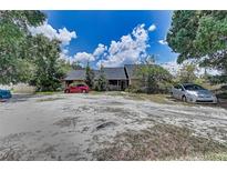 Exterior view of a single-story home on a large lot with multiple cars parked in the front driveway at 11624 Delmar Ave, Orlando, FL 32836