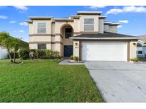 Two-story home featuring a well-manicured lawn, a two-car garage, and a neutral-colored facade at 12543 Waterhaven Cir, Orlando, FL 32828