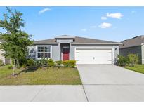 Charming single Gathering home featuring a 2-car garage, landscaped yard, and red front door at 3341 Lounging Wren Ln, Bartow, FL 33830