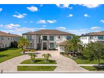 Stunning luxury home featuring a circular paver driveway, lush landscaping, and a grand facade at 4047 Isabella Cir, Windermere, FL 34786