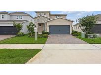 Charming two-story home with stone accents, a well-manicured lawn, and a brick driveway at 4338 Davos Dr, Clermont, FL 34711