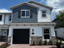 Two-story townhome featuring stone accents, a black garage door, and a mix of blue and white siding at 5103 Prairie Preserve Run, St Cloud, FL 34772