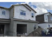 Construction of a two-story townhome with Tyvek wrap and an attached garage on a partly cloudy day at 5103 Prairie Preserve Run, St Cloud, FL 34772