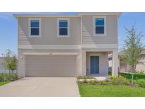 Charming two-story home featuring a tidy lawn, an attached two-car garage, and a welcoming blue front door at 5109 Forget Me Not Ave, Lake Hamilton, FL 33851
