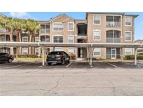 Condo building exterior showing a covered parking area, neutral color scheme, and manicured landscaping with palm trees at 7147 Yacht Basin Ave # 119, Orlando, FL 32835