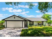 Charming single-story home with a lush lawn, brick driveway, and attached two-car garage at 7664 Clubhouse Estates Dr, Orlando, FL 32819