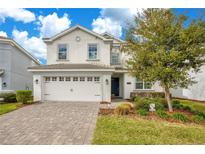 Charming two-story home featuring a paver driveway, two-car garage, and well-maintained landscaping at 9034 Stinger Dr, Davenport, FL 33896