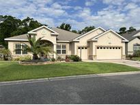 Charming single-story home featuring stucco siding, a manicured lawn, and a well-maintained three car garage at 11120 Se 168Th Loop, Summerfield, FL 34491