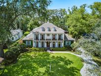 Stately two-story home featuring a manicured lawn, dormer windows, and light blue shutters, exuding classic elegance at 1400 Place Picardy, Winter Park, FL 32789