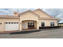 Inviting exterior featuring a light tan color scheme, red tiled roof, and attached garage at 2612 Shantiniketan Blvd # G12, Tavares, FL 32778