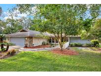 Charming home featuring a stone accent wall on the garage and a lush front yard with mature landscaping at 311 Needles Trl, Longwood, FL 32779