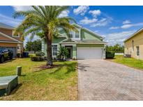 Charming two-story home with green siding, brick driveway, and a well-maintained front yard at 344 Cadiz Loop, Davenport, FL 33837