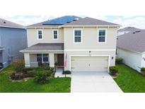 Charming two-story home with a manicured lawn, two-car garage, and modern solar panels at 9040 Alba Ln, Kissimmee, FL 34747