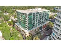 Modern high-rise condo building with walls of windows and balconies, surrounded by lush greenery and palm trees at 101 S Eola Dr # 812, Orlando, FL 32801