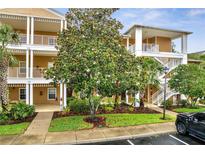 Condo exterior features well-maintained landscaping, white railing balconies, and a beautifully flowering tree at 510 Rum Run # 33 510, Davenport, FL 33837