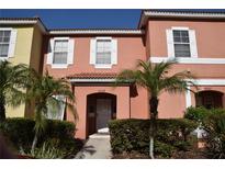Charming townhome featuring a red-toned facade, white trim, and well-maintained landscaping at 8564 Bay Lilly Loop, Kissimmee, FL 34747