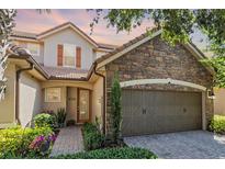 Charming home showcasing stone accents, a two-car garage, and a beautifully landscaped front yard at 10533 Belfry Cir, Orlando, FL 32832