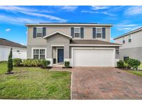 Charming two-story home featuring a brick driveway, attached garage, and well-maintained landscaping at 178 Aria Way, Davenport, FL 33837