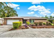 Charming brick home featuring a well-manicured lawn, a two-car garage, and a welcoming front entrance at 28136 Tammi Dr, Tavares, FL 32778