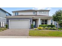 Beautiful two-story home with a brick driveway, lush landscaping, and a charming front porch at 3294 Hanging Tide St, Winter Garden, FL 34787