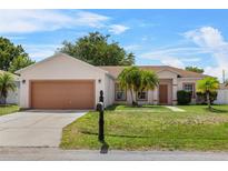 Charming single-story home with a well-maintained lawn, lovely palm trees, and two-car garage at 504 Delido Way, Kissimmee, FL 34758