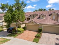 Charming townhome featuring a tile roof, brick driveway, and lush landscaping at 8539 Via Bella Notte, Orlando, FL 32836
