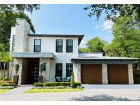 Modern two-story home showcasing stone accents, a two-car garage, and manicured landscaping at 1831 Mizell Ave, Winter Park, FL 32789