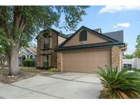 Two-story house featuring a two-car garage, tan exterior paint, and well-maintained landscaping at 2239 Meadowmouse St, Orlando, FL 32837