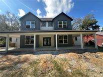 Two-story home featuring gray vertical siding, a covered porch with white columns and green double doors at 335 Ruth Blvd, Longwood, FL 32750