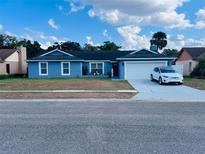 Charming single-story home featuring a blue exterior, well-maintained landscaping, and an attached two car garage at 6216 Beaumont Ave, Orlando, FL 32808