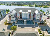 Beautiful aerial view of new condos by a lake with ample parking spaces and lush landscaping at 7565 Laureate Blvd # 3408, Orlando, FL 32827