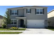 Two-story home featuring a two-car garage, well-manicured lawn, and freshly painted exterior with stylish shutters at 919 Princess Sabal Pt, Haines City, FL 33844