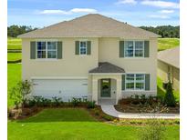 Charming two-story home with a manicured lawn, attached garage, and welcoming entryway at 947 Princess Sabal Pt, Haines City, FL 33844