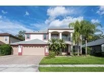 Charming two-story home featuring a brick driveway, lush landscaping, and a second-floor balcony at 16500 Cedar Run Dr, Orlando, FL 32828