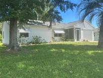 Charming single-story home with a well-maintained lawn, lush trees and a screened in porch at 1707 E Schwartz Blvd, Lady Lake, FL 32159