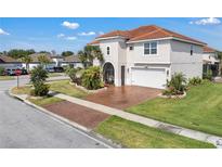 Beautiful two-story home with a terracotta roof, a brick driveway, manicured landscaping, and a two-car garage at 3966 Steer Beach Pl, Kissimmee, FL 34746