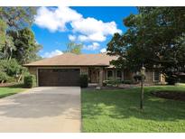 Charming single-story home with a well-manicured lawn, mature trees, and a paved driveway at 477 Eagle Brook Ct, Debary, FL 32713