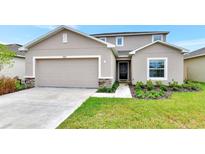 Charming two-story home featuring a well-manicured lawn, a stone-accented facade, and a two-car garage at 4792 Vellacito Way, Davenport, FL 33897