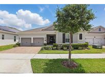 Charming single-story home featuring a brick driveway, two-car garage, and well-maintained landscaping at 5427 Orange Orchard Dr, Winter Garden, FL 34787