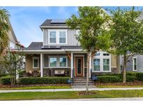Charming two-story home featuring a cozy front porch, stone accents, solar panels, and well-maintained landscaping at 7873 Dausset St, Orlando, FL 32827