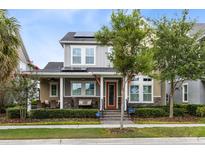 Charming two-story home boasts a welcoming front porch, solar panels, manicured landscaping, and classic architectural details at 7873 Dausset St, Orlando, FL 32827