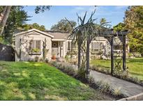 Charming home featuring a well-manicured front yard, a decorative pergola, and beautiful landscaping at 100 Kennison Dr, Orlando, FL 32801